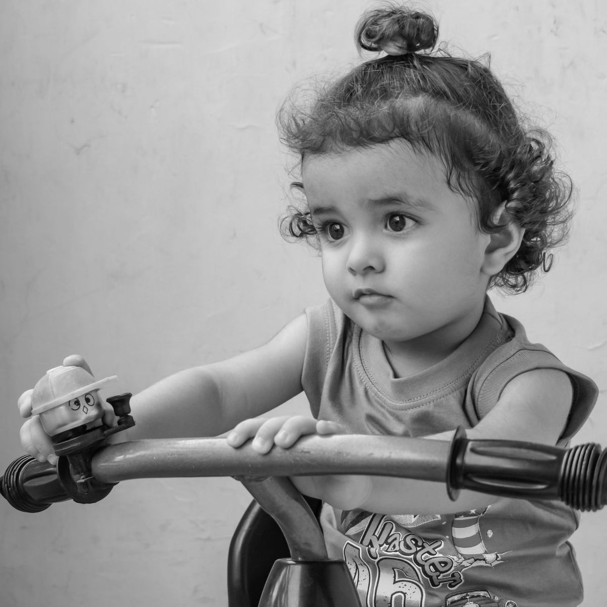 Black and white portrait of a cute toddler on a toy bike showcasing innocence and playfulness.