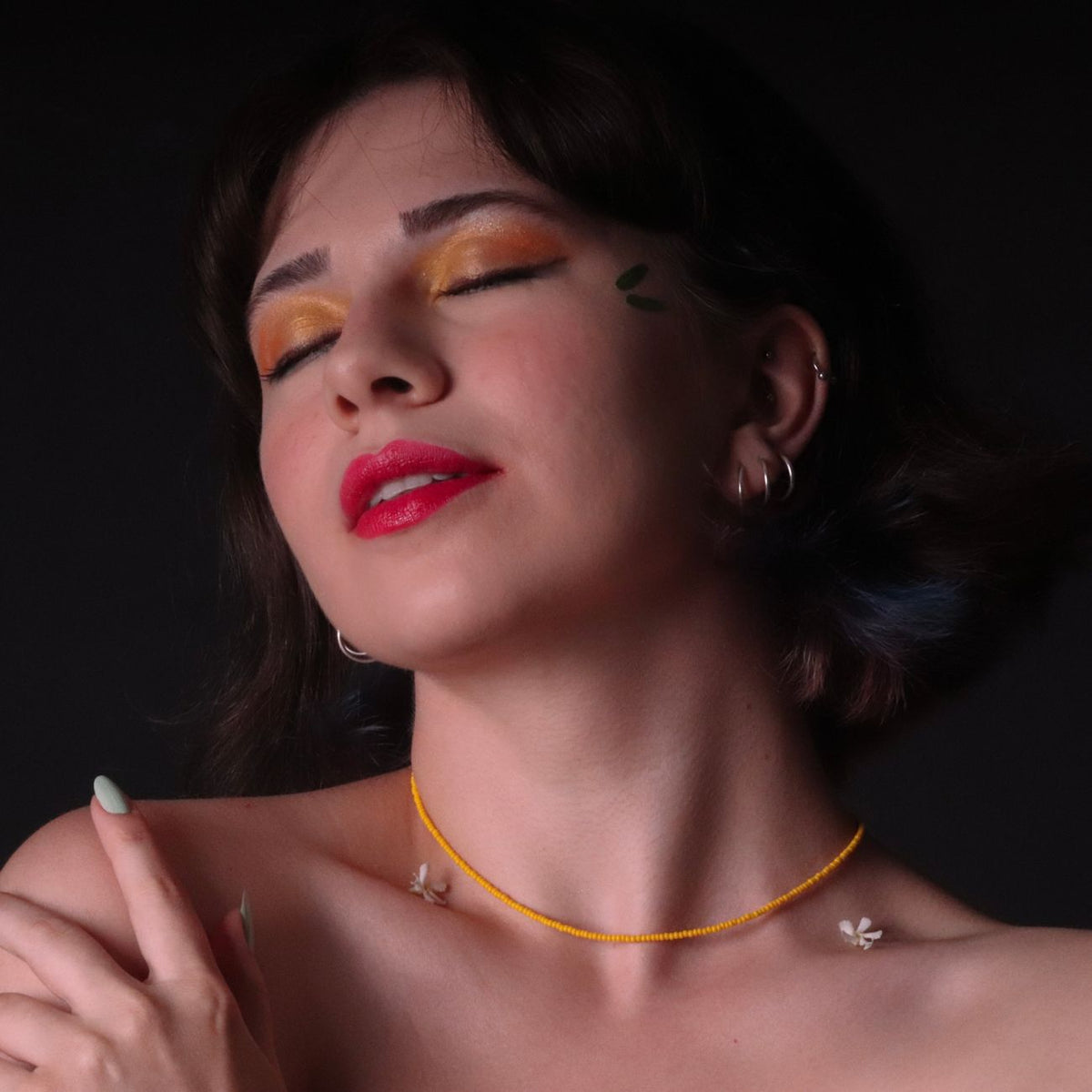 Close-up studio portrait of a woman with vibrant makeup and accessories.