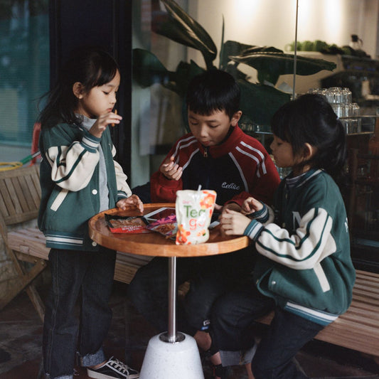Three children enjoy snacks together at a table in Hà Giang, Vietnam.