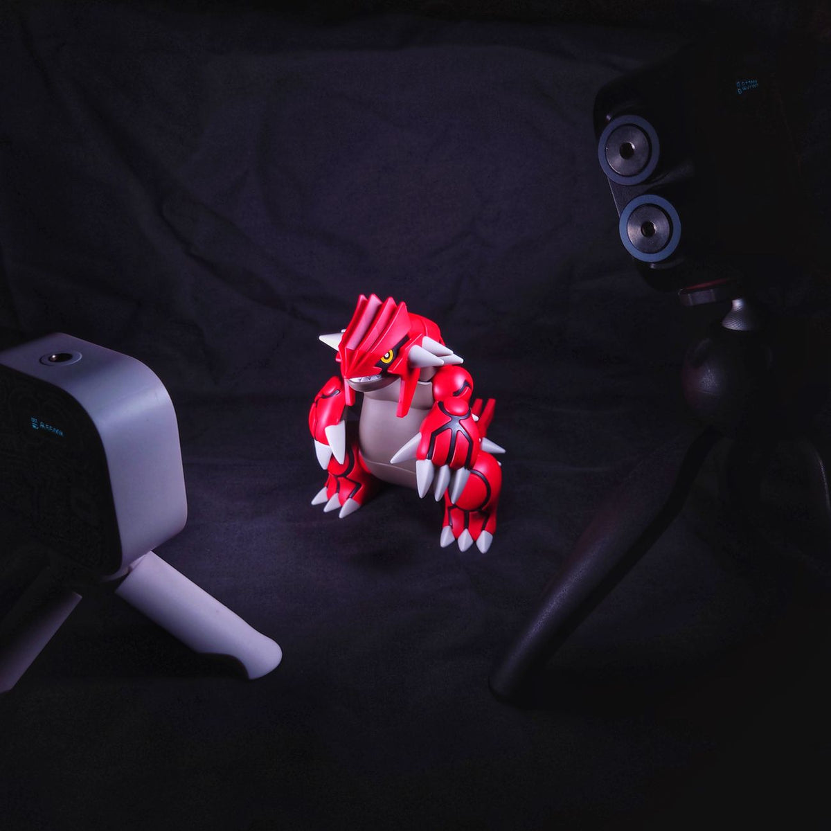 A red dinosaur figurine captured in dramatic studio lighting with camera equipment.