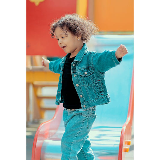 A joyful child wearing a denim jacket enjoys time at the playground slide.