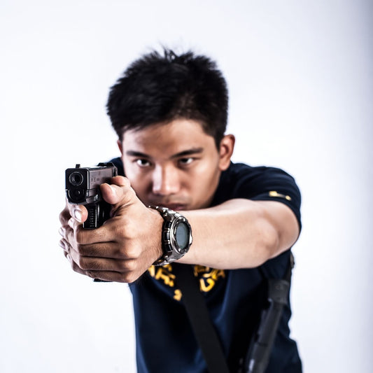 Focused young man aiming a gun in a studio setting, emphasizing intensity.