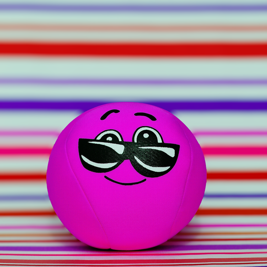 A bright pink smiley face ball wearing sunglasses on a colorful striped background.