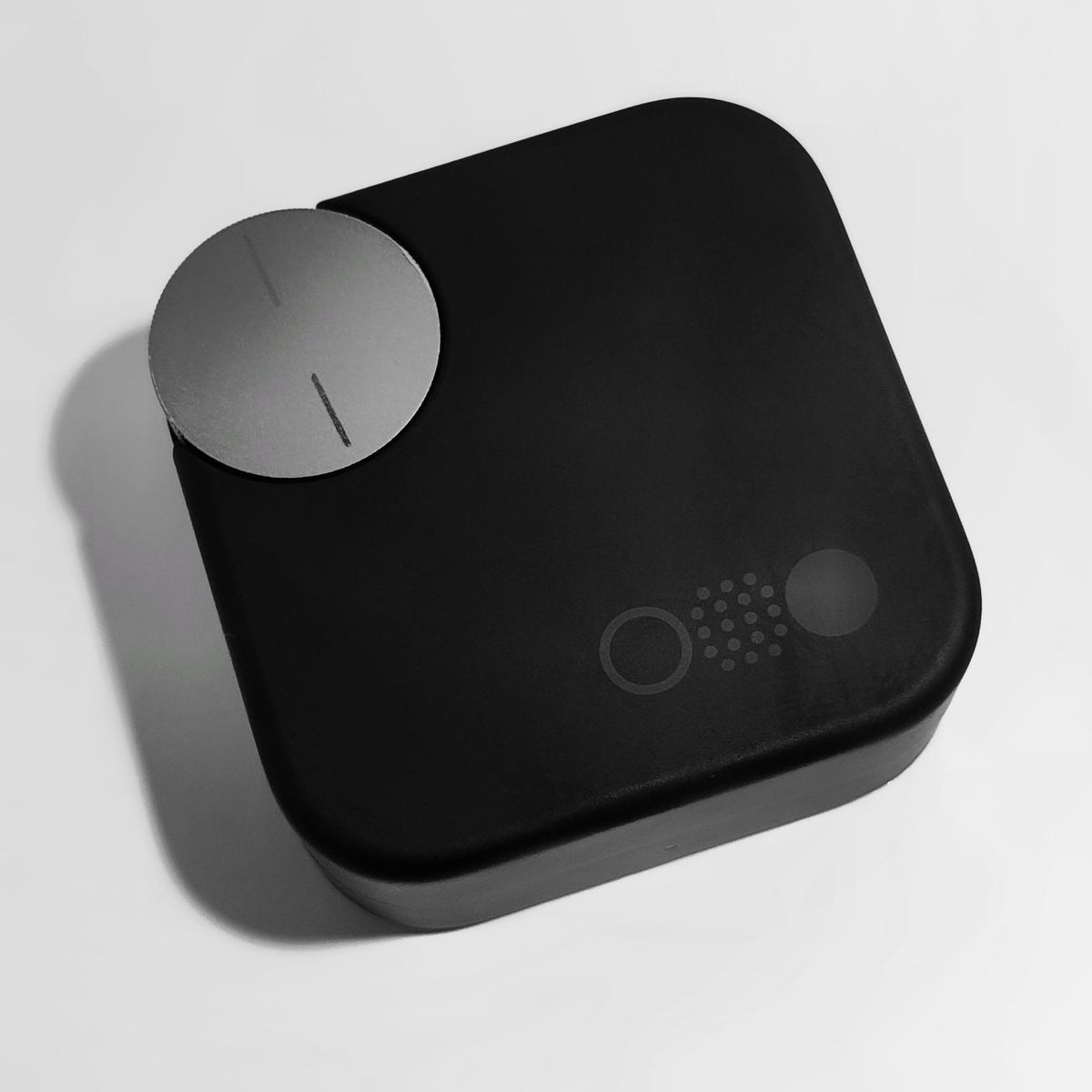 Minimalistic product shot of a black wireless audio device with sleek design on a white background.