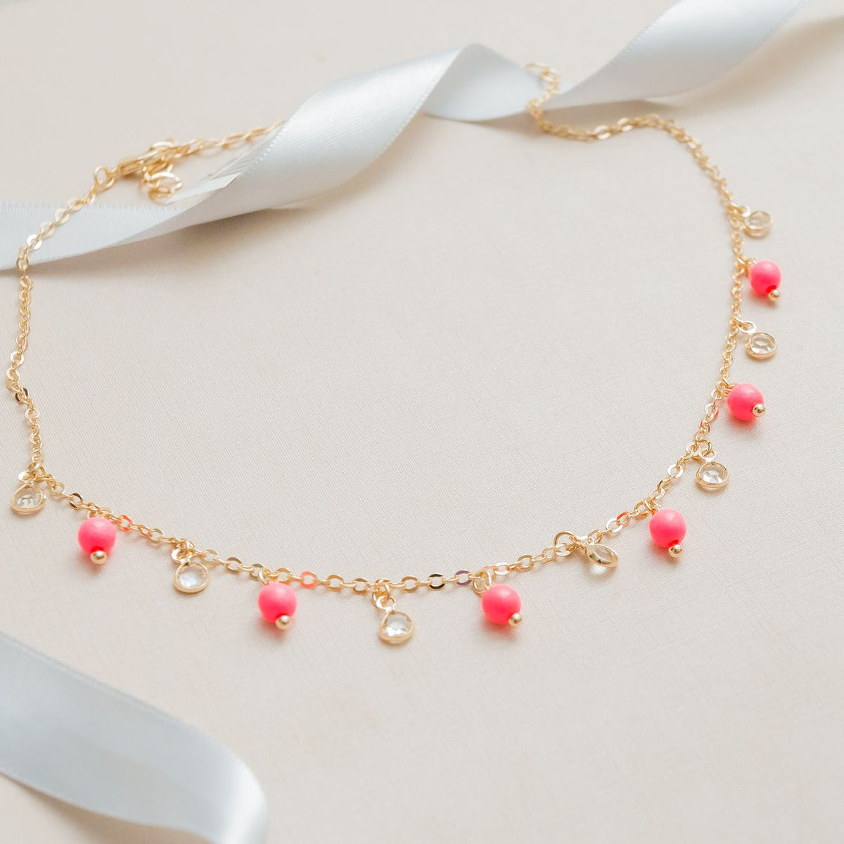 Chic gold necklace adorned with pink and clear beads, perfect for jewelry showcases.