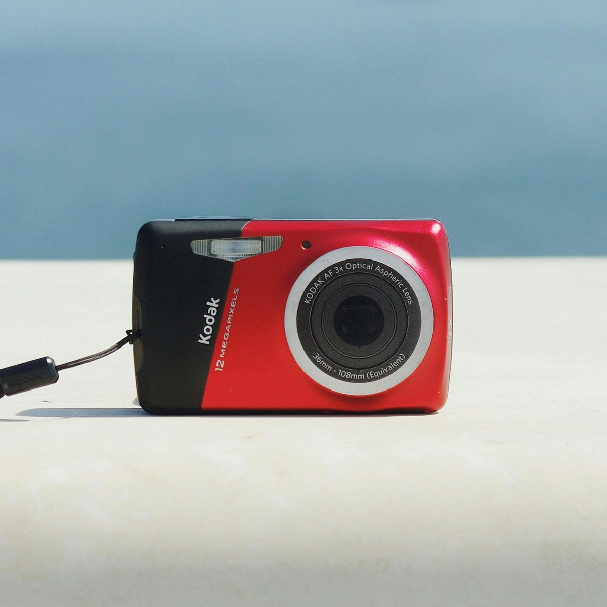 Close-up of a red Kodak digital camera against a simple backdrop, capturing minimalistic design.