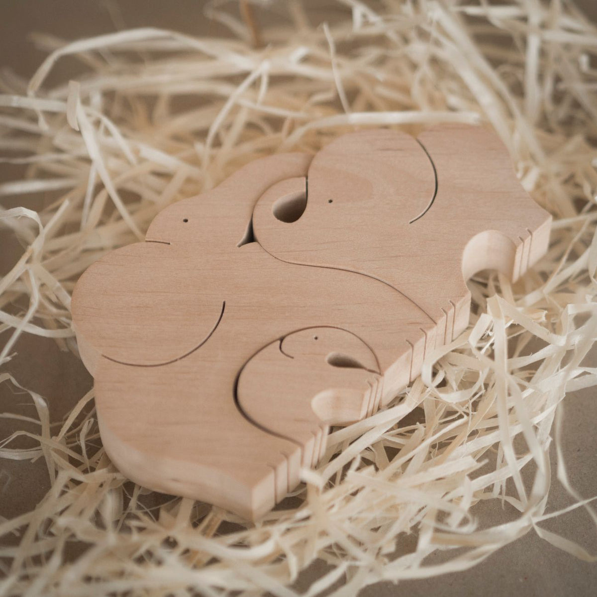 Rustic wooden elephant puzzle toy surrounded by straw, showcasing artisan craftsmanship.