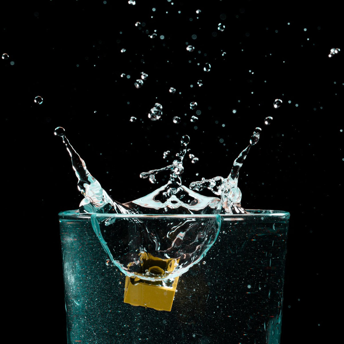 Close-up of a water splash in a glass against a black background, capturing motion.